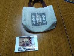 県社の新たな神輿がプリントされたポストカード（写真下）と社トートバッグの試作品（写真上）